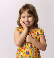 Young girl wearing a yellow dress with a pattern of cartoon characters on a white background