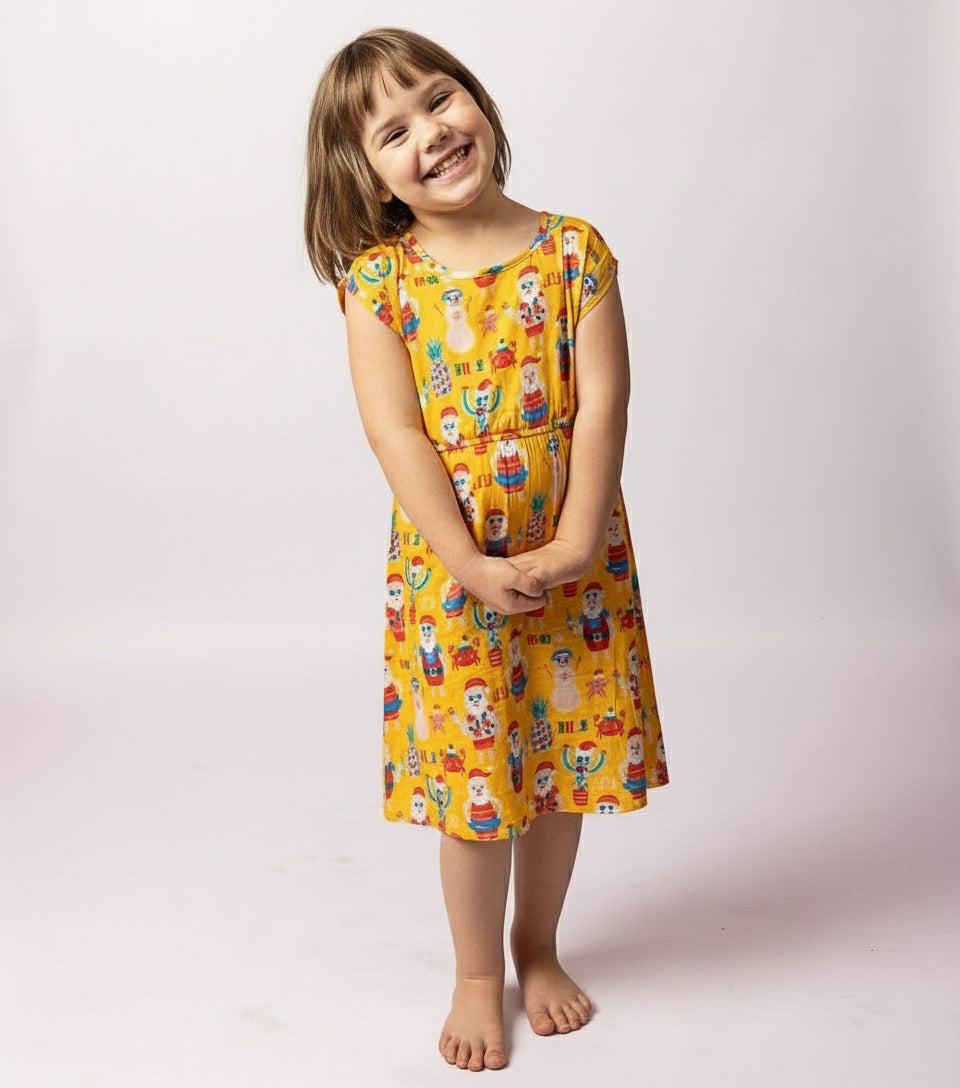 Young girl wearing a yellow dress with cartoon character print on a white background
