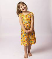 Young girl wearing a yellow dress with cartoon character print on a white background