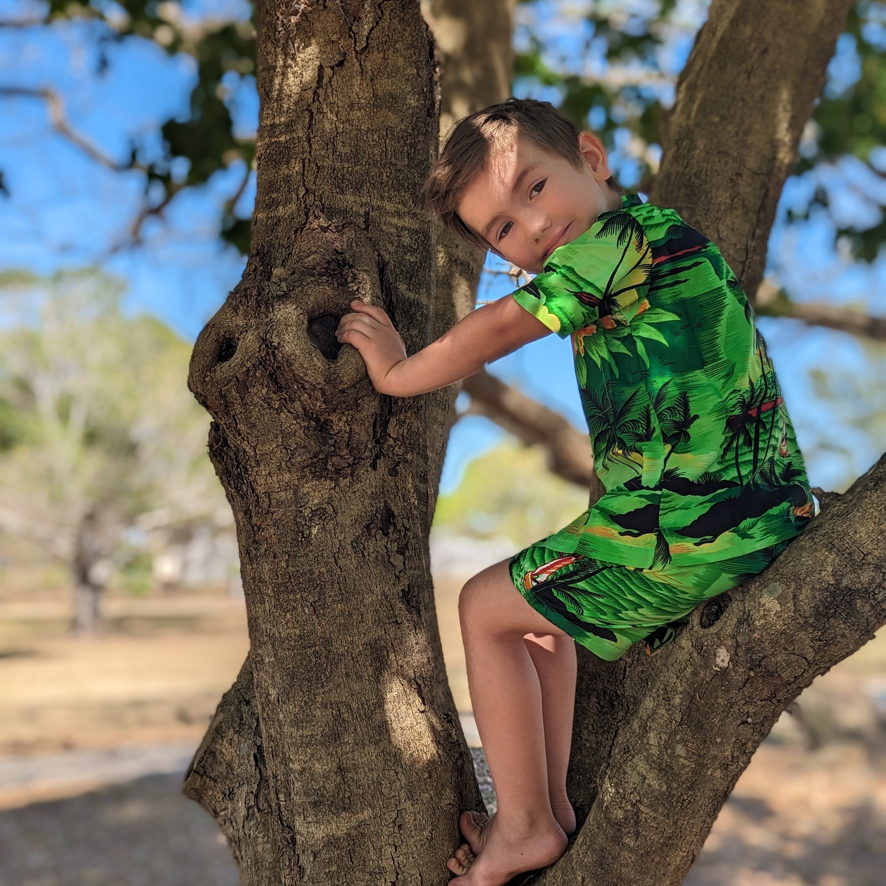Sunset Green Kids Shirt with tropical-themed pattern; short sleeves, bright festive colors. | Tropicool Clothing