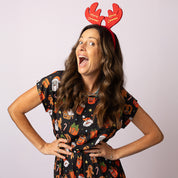 Woman wearing the Tropicool Alice JingleVerse Christmas adult dress in black rick & morty theme, smiling with festive antlers.