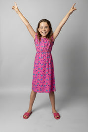 Young girl wearing a pink dress with retro vibe pattern on a white background